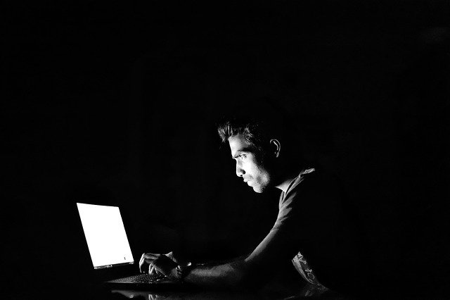 暗闇でコンピューターを操作する男性